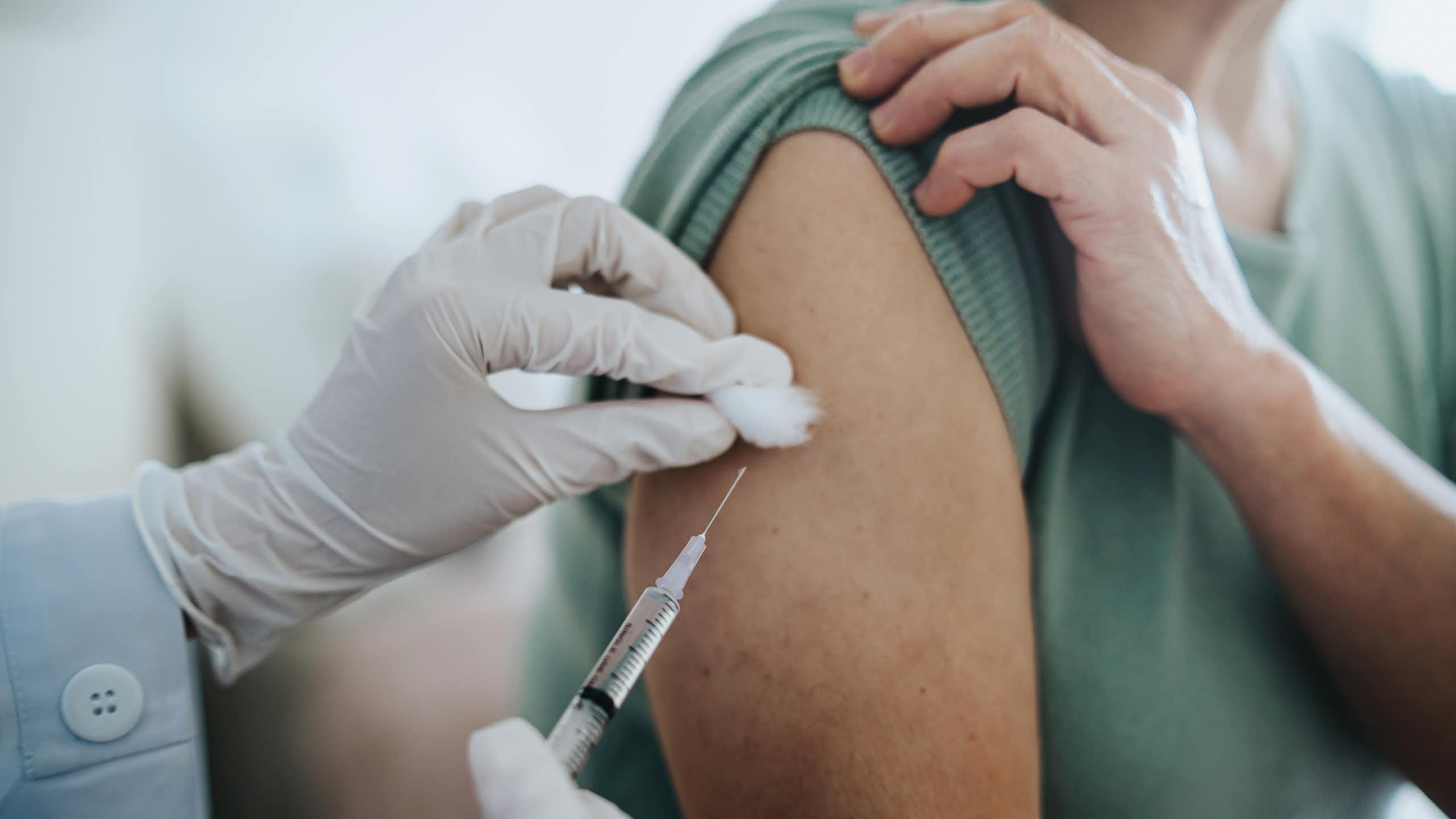 Close-up of someone getting a shot in their arm.