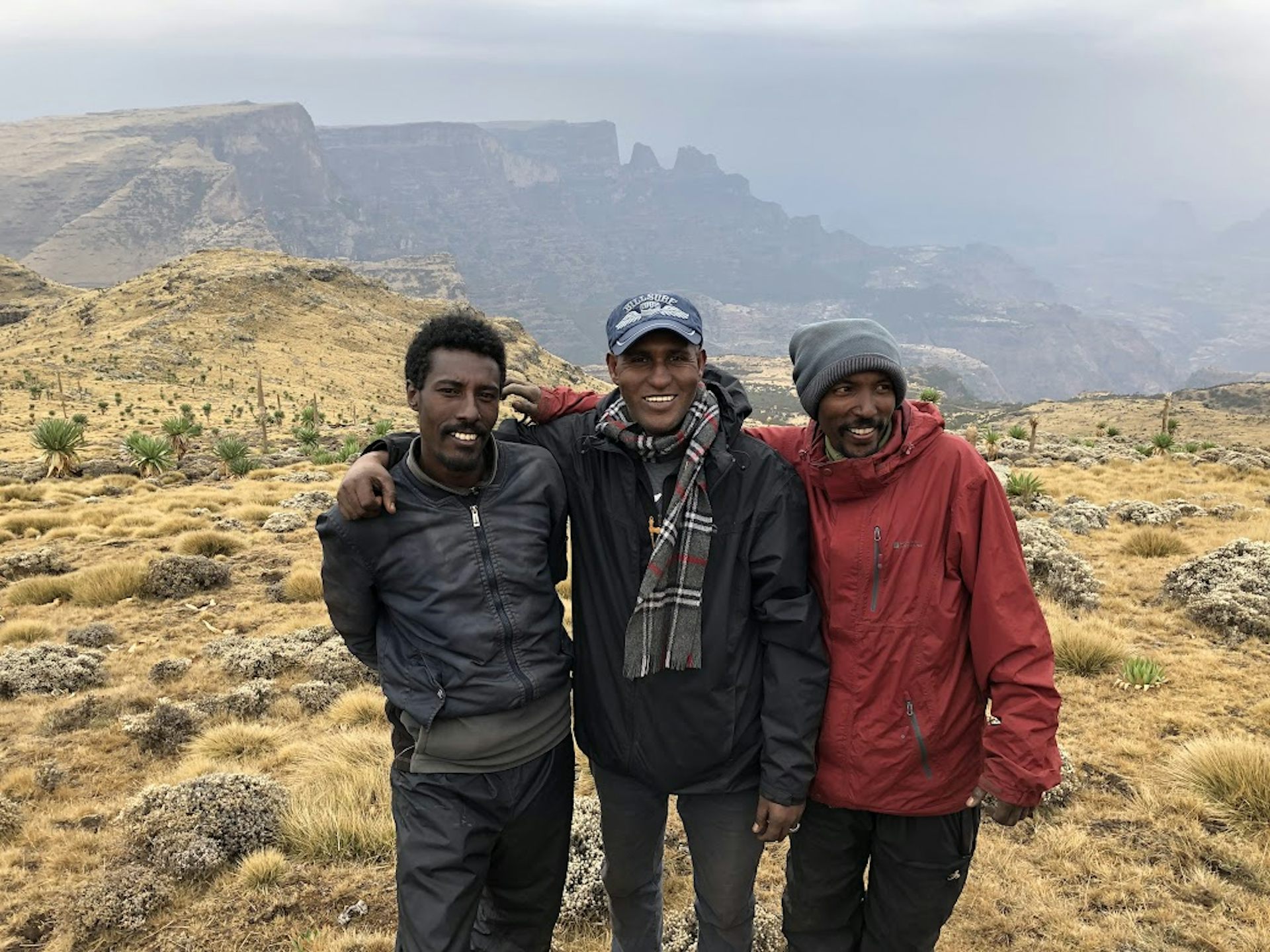 Three men standing on the top of a high mountain