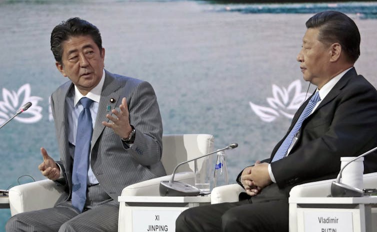 Why Japan’s toughen for Taiwan has long past down so badly in China 2 Shinzo Abe and Xi Jinping sat next to each other.