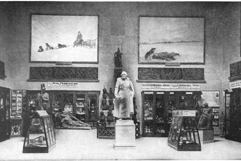 Statue on a pedestal surrounded by images on walls and some items in cases.