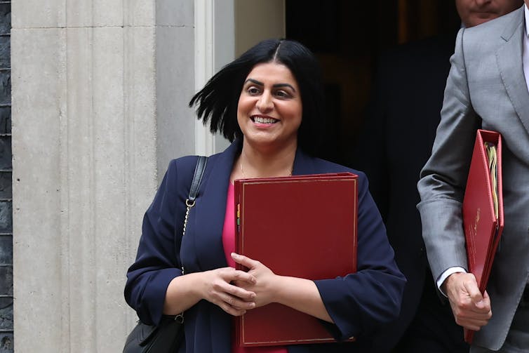 A smiling Shabana Mahmood walks out of Downing Street with a red folder