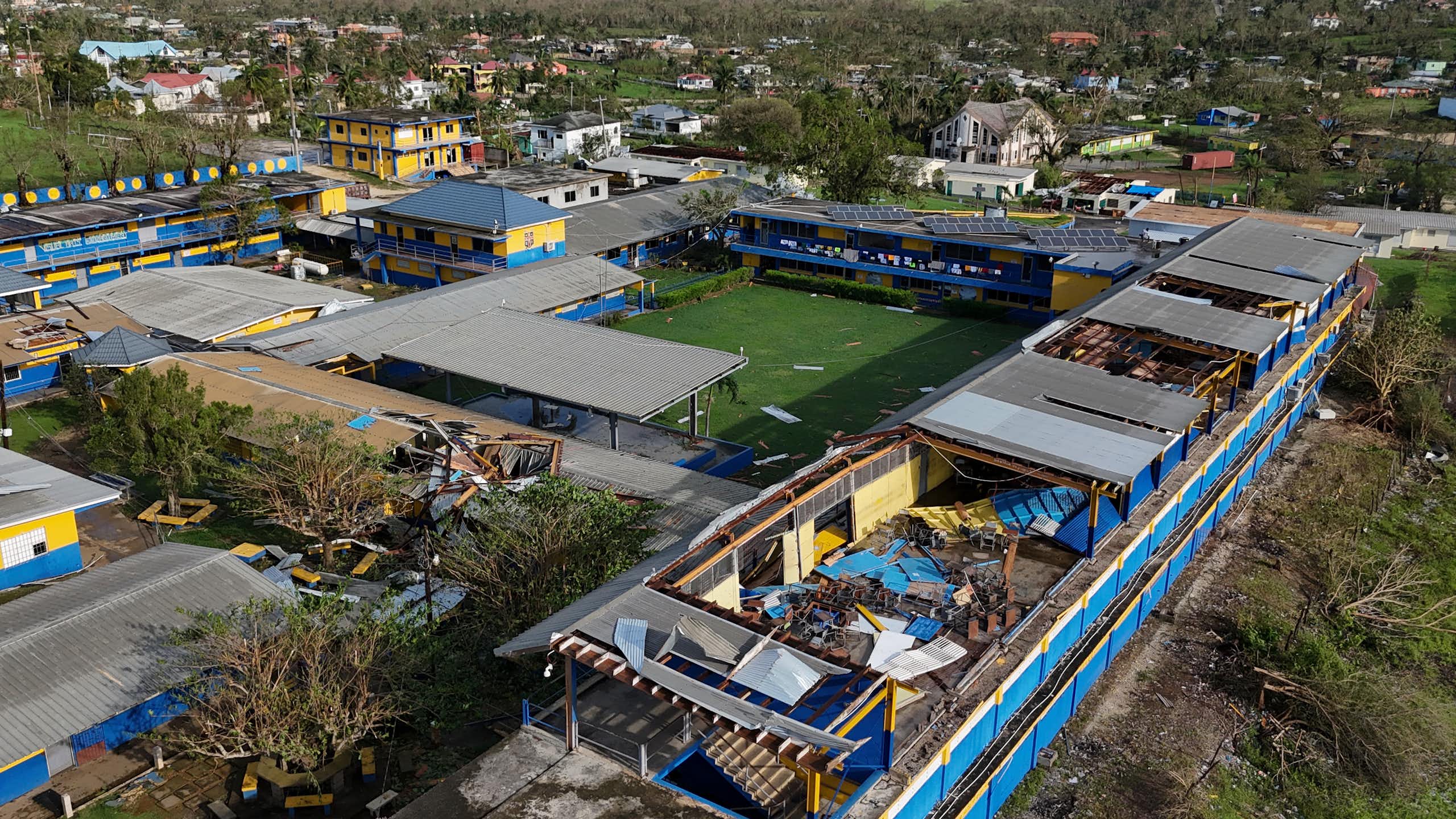 A building showing part of a missing roof near a school field.