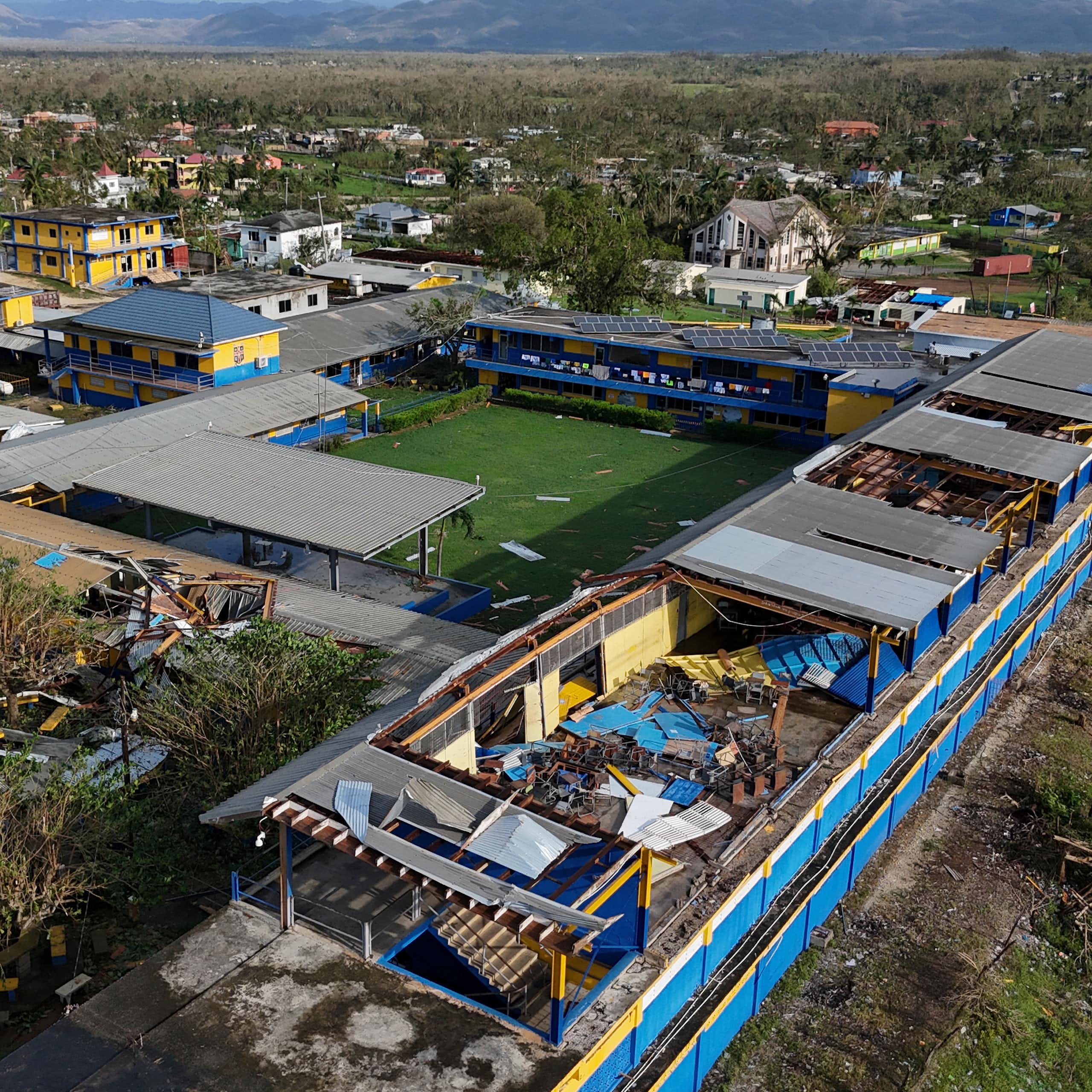 A building showing part of a missing roof near a school field.