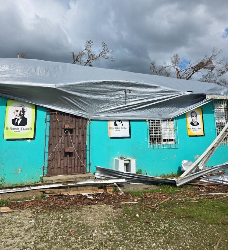 Un edificio con una lona y escombros esparcidos al frente.