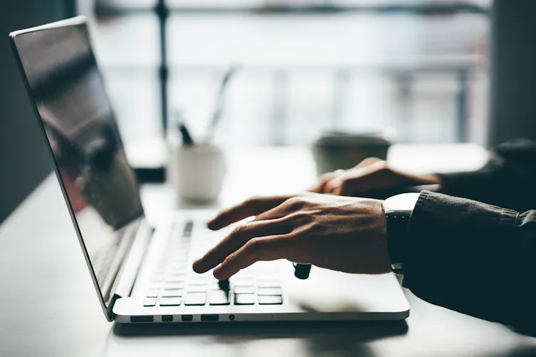Someone writes using a laptop in a hazy photo.