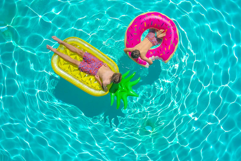 Two boys floating on pool toys in pool