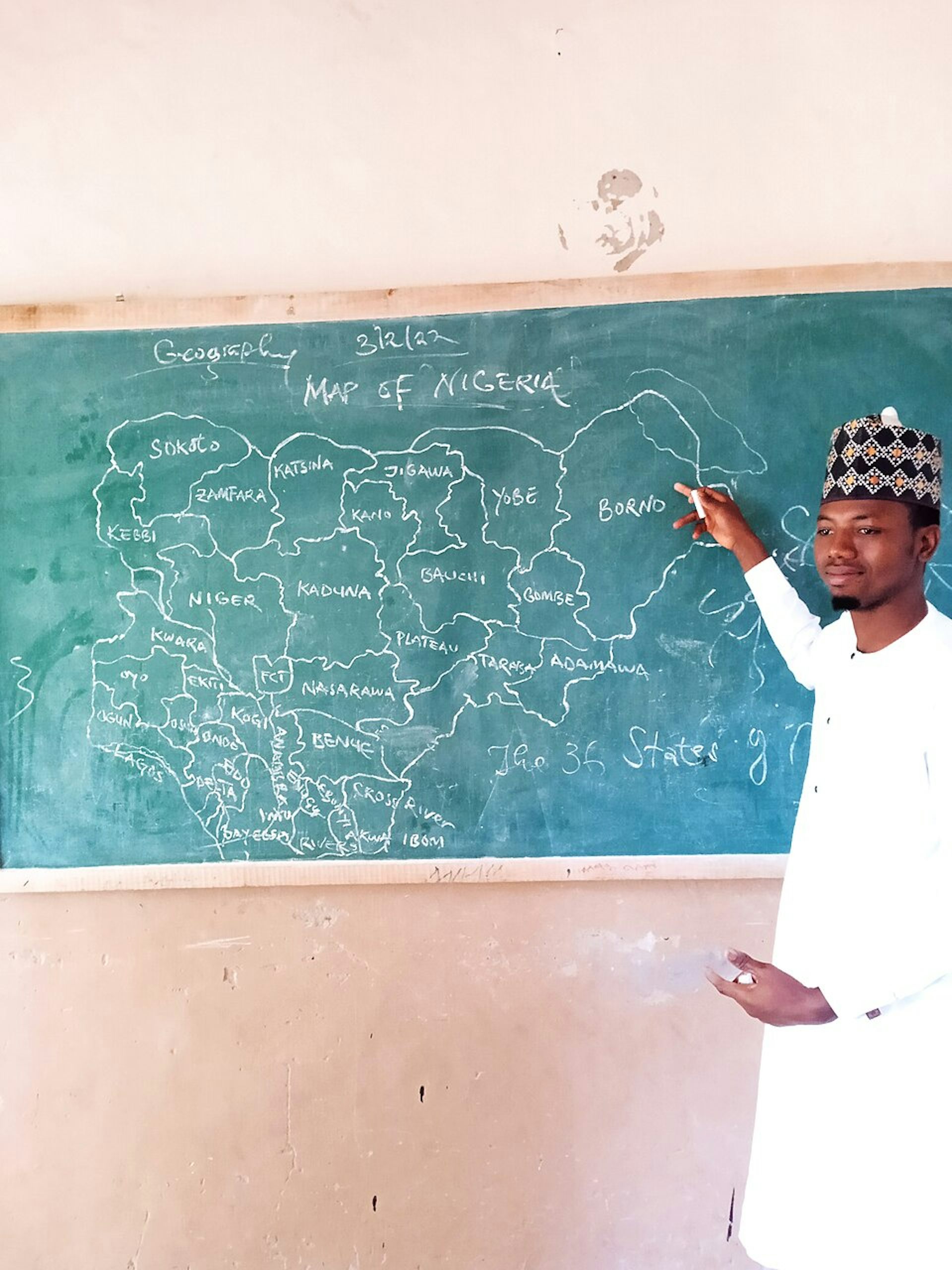 Man pointing to map of Nigeria on a chalkboard