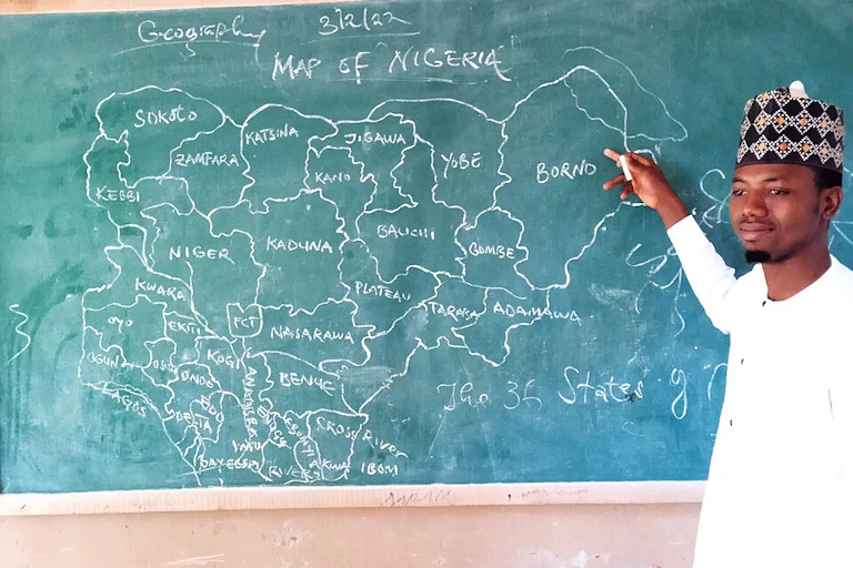 Man pointing to map of Nigeria on a chalkboard