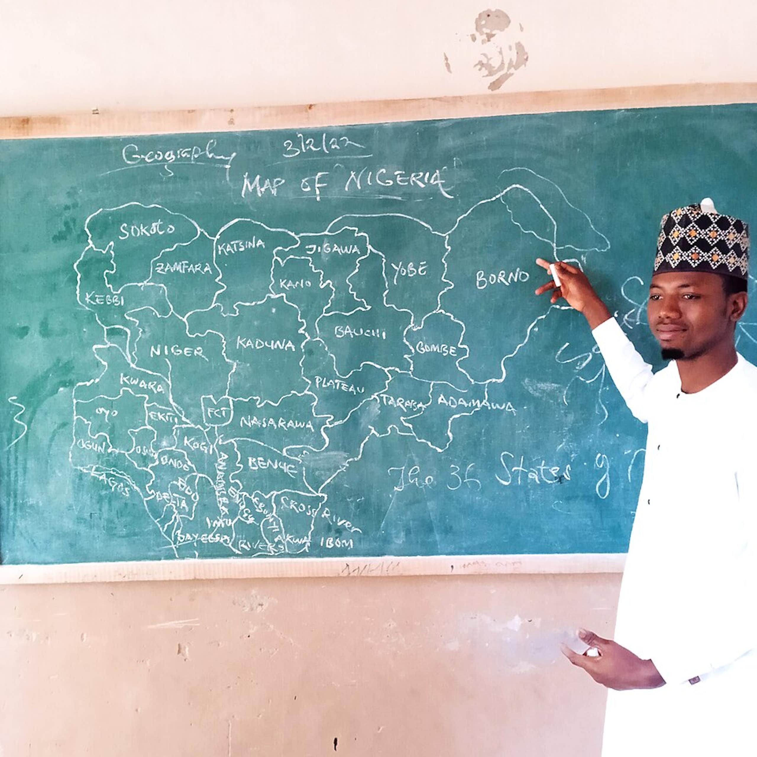 Man pointing to map of Nigeria on a chalkboard