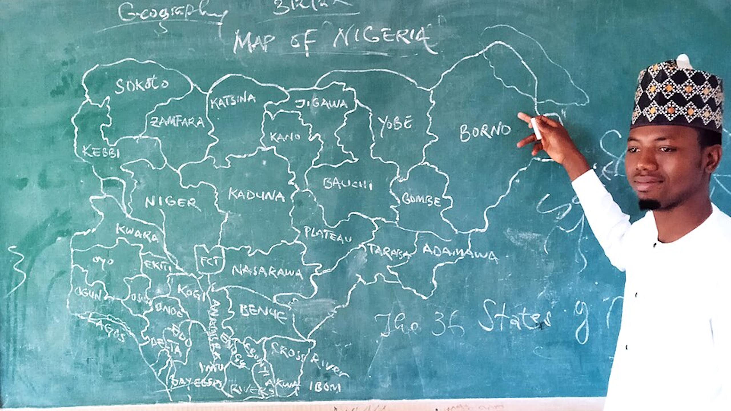 Man pointing to map of Nigeria on a chalkboard
