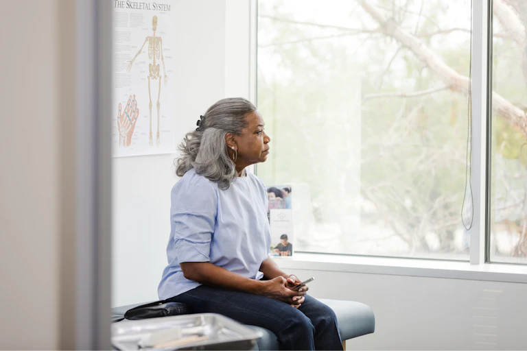 Woman sits on bed in hospital clinic room