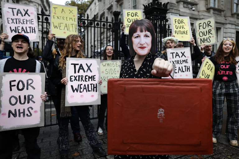 protester at downing street with a rachel reeves mask and a mock red briefcase.