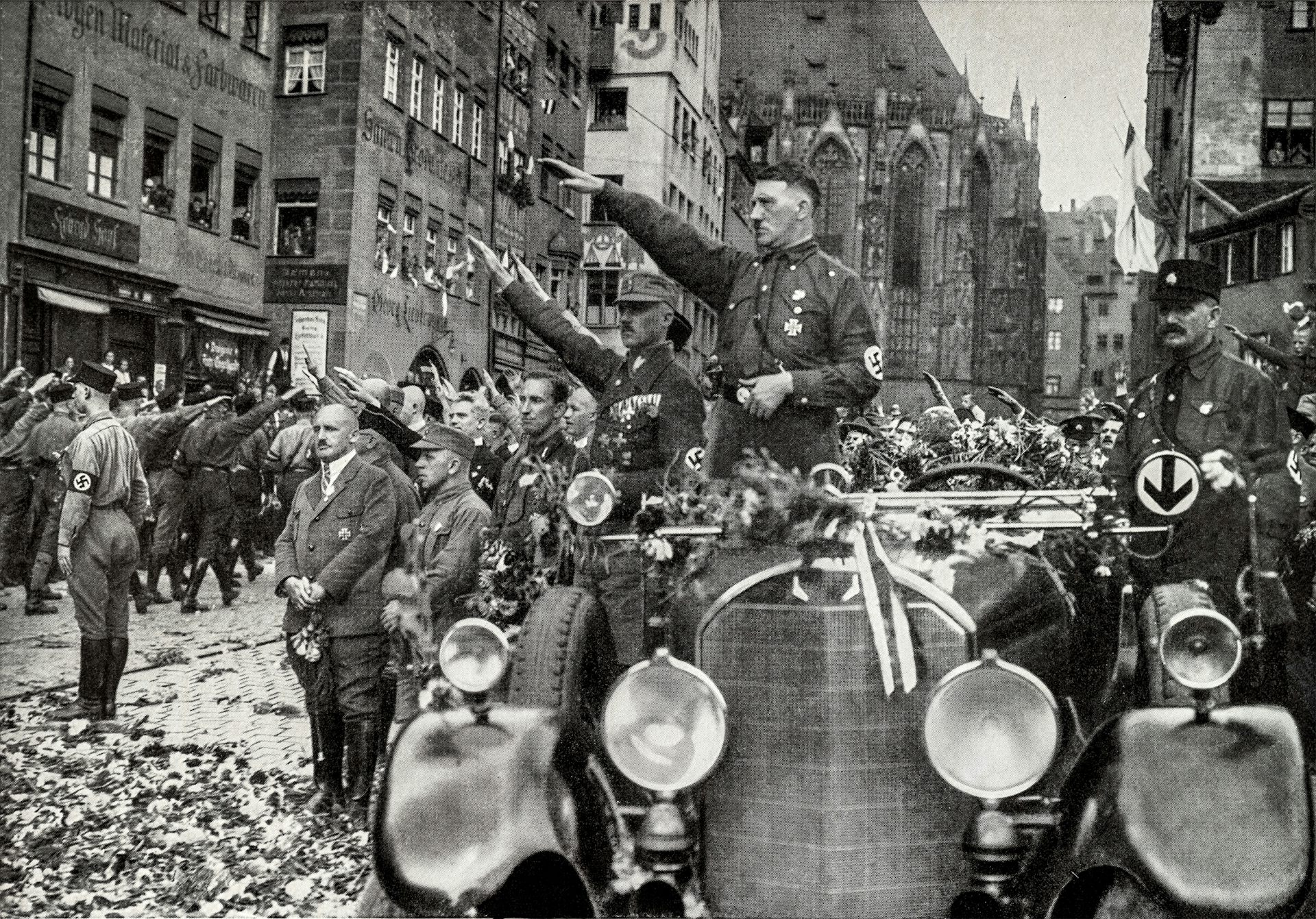 Adolf Hitler gives the Nazi salute from his car.