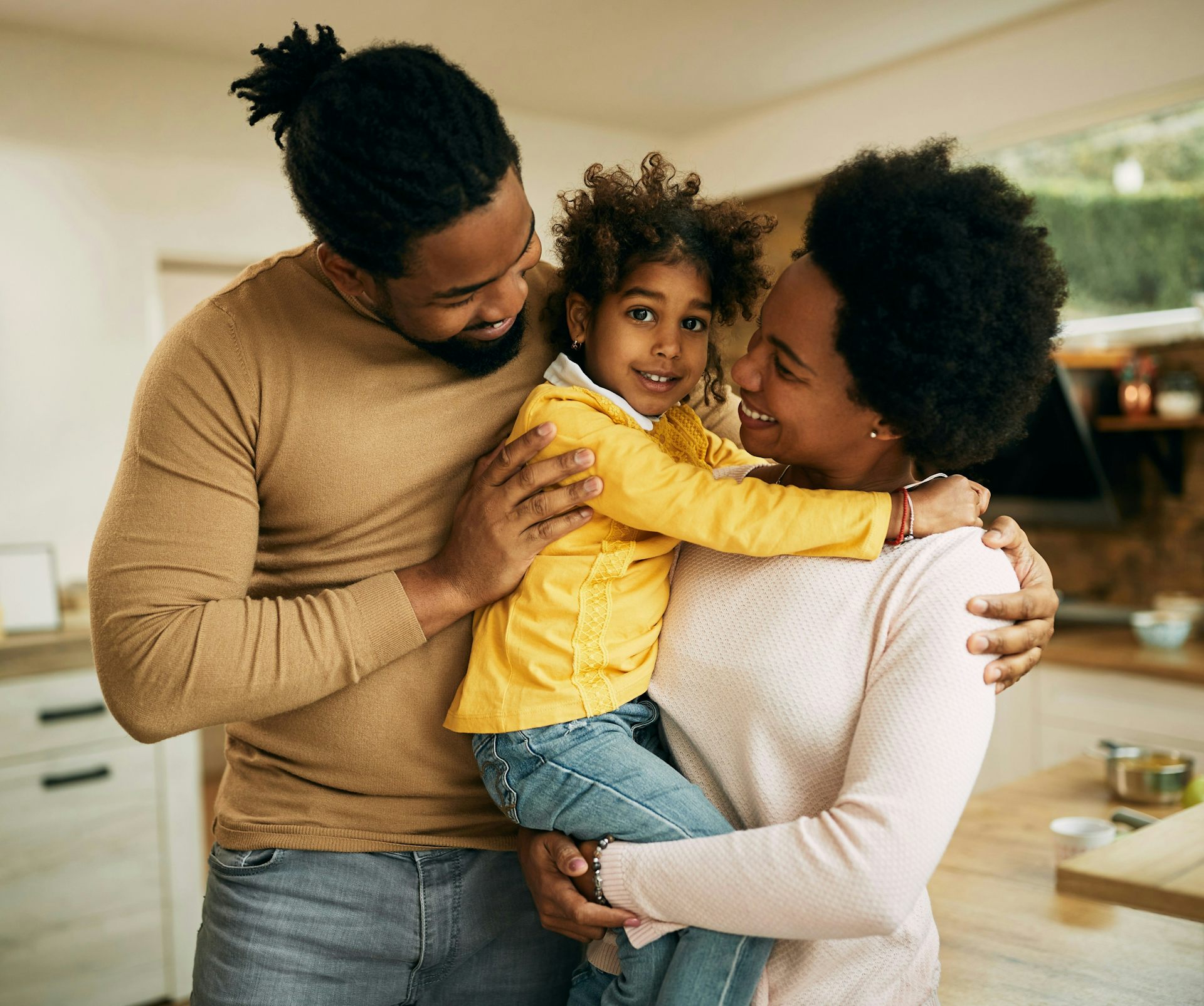 Una pareja y su hijo están en la cocina y se abrazan.
