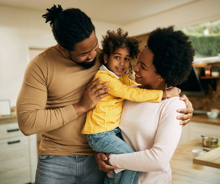 Una pareja y su hijo están en la cocina y se abrazan.
