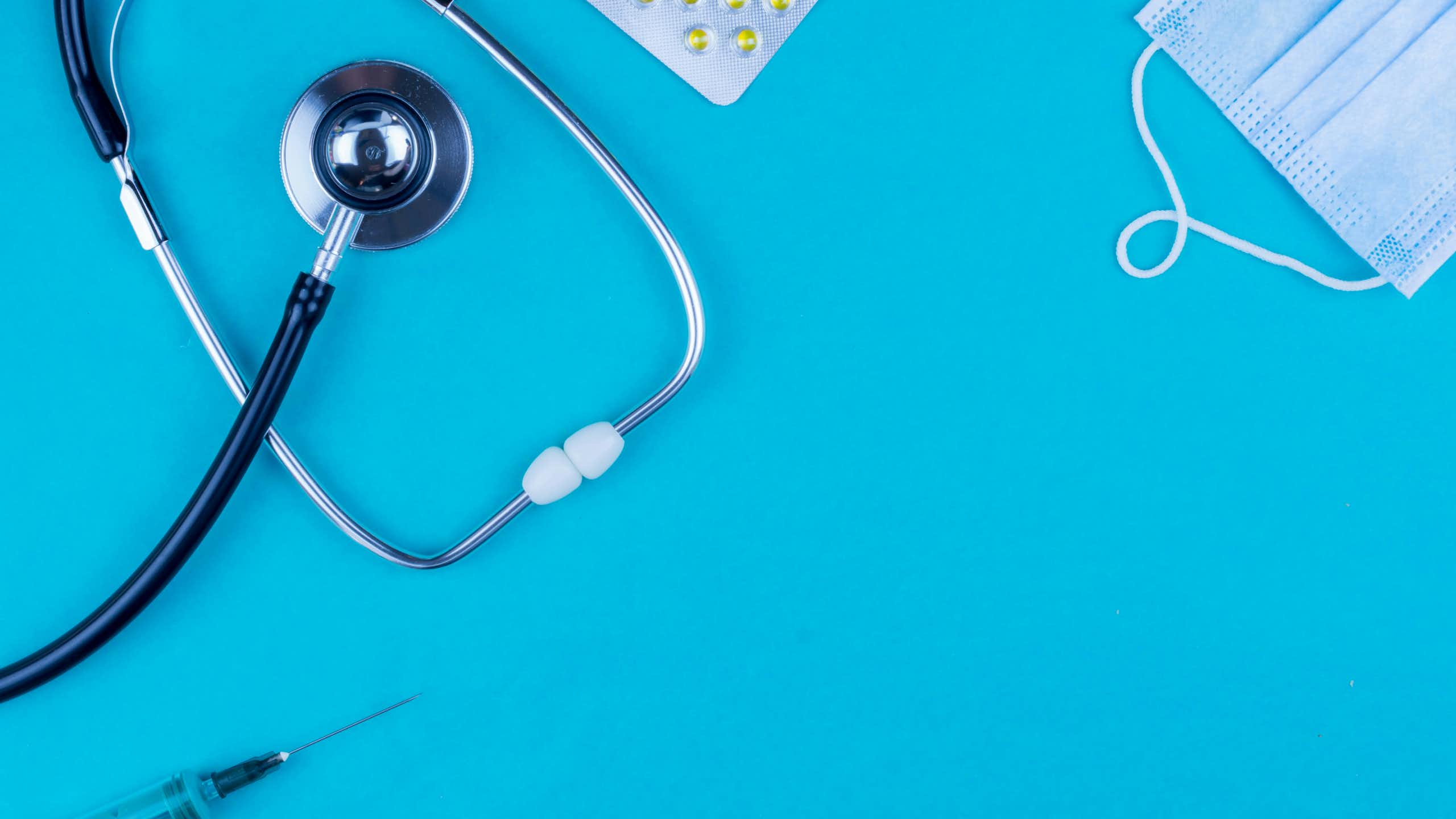 A stethoscope, a mask, pills and a syringe displayed.