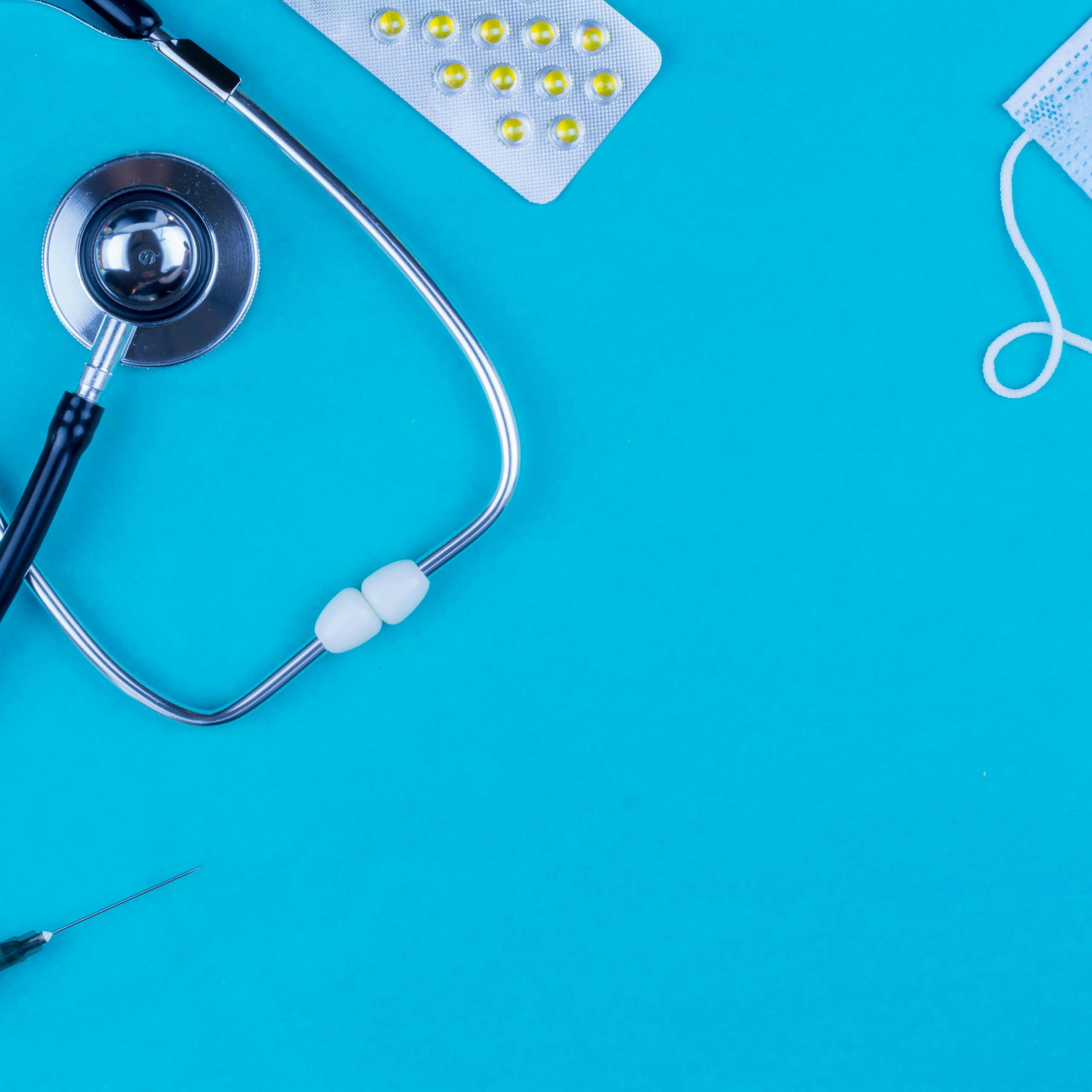 A stethoscope, a mask, pills and a syringe displayed.