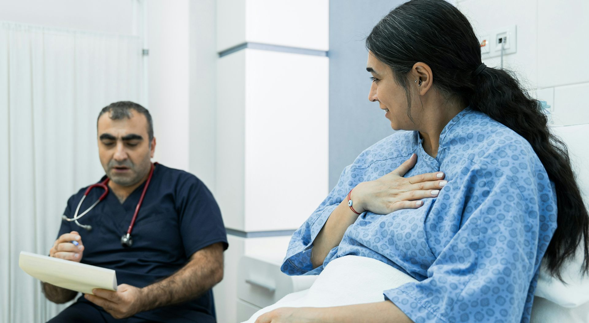 El médico se sienta junto a la cama del paciente.