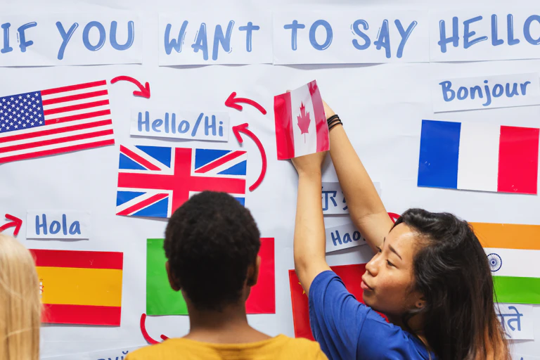 three people stood at wall with colourful country flags, words on board spell ' if you want to say hello'