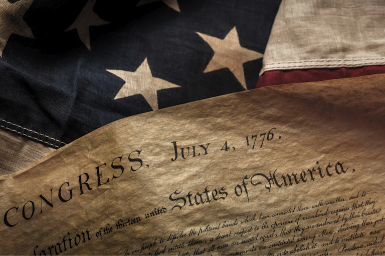 Declaration of independence is seen in front of U.S. flag.