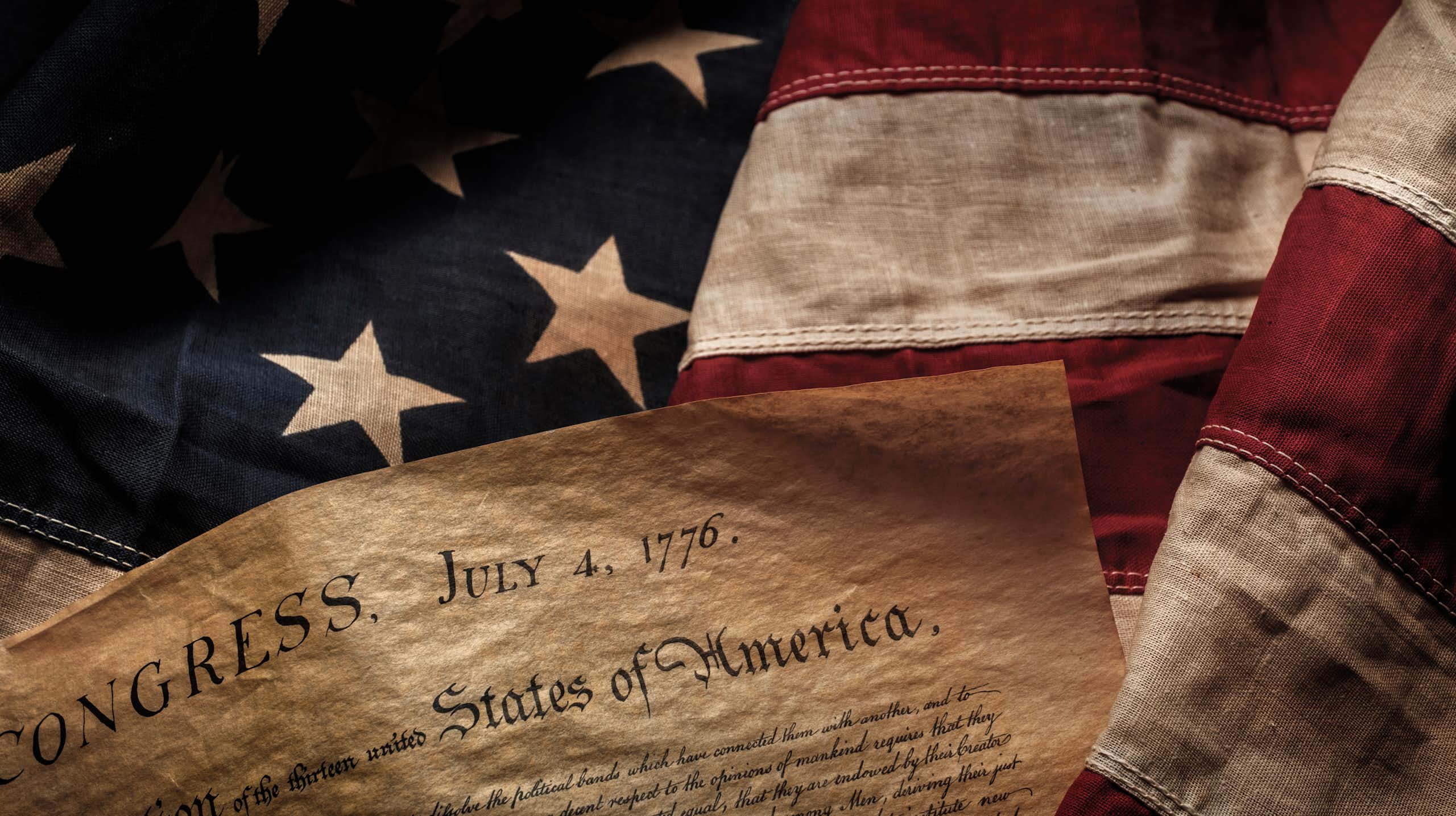 Declaration of independence is seen in front of U.S. flag.
