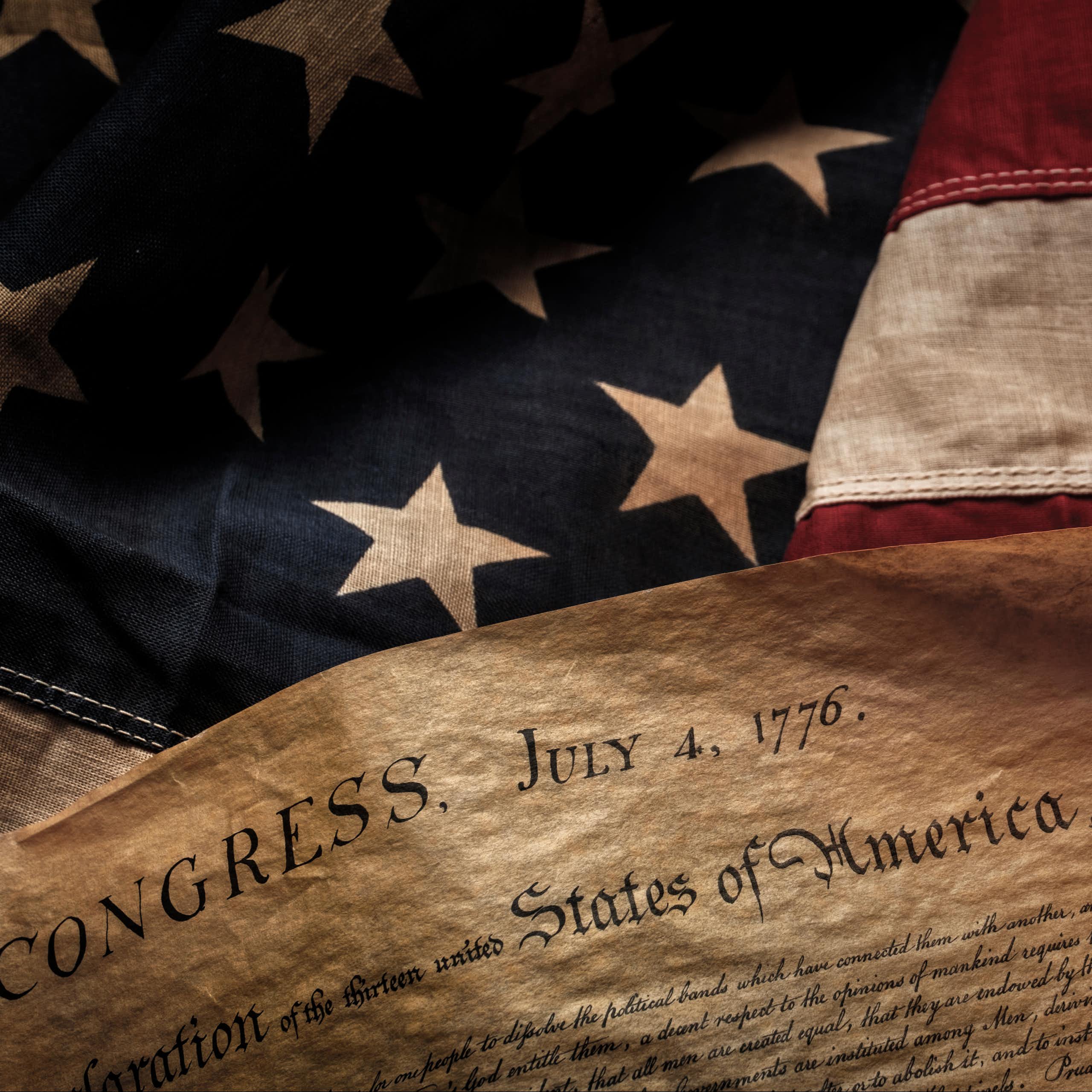 Declaration of independence is seen in front of U.S. flag.
