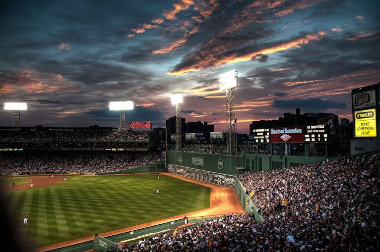 A view across the stands during a game at Fenway Park under the lights.