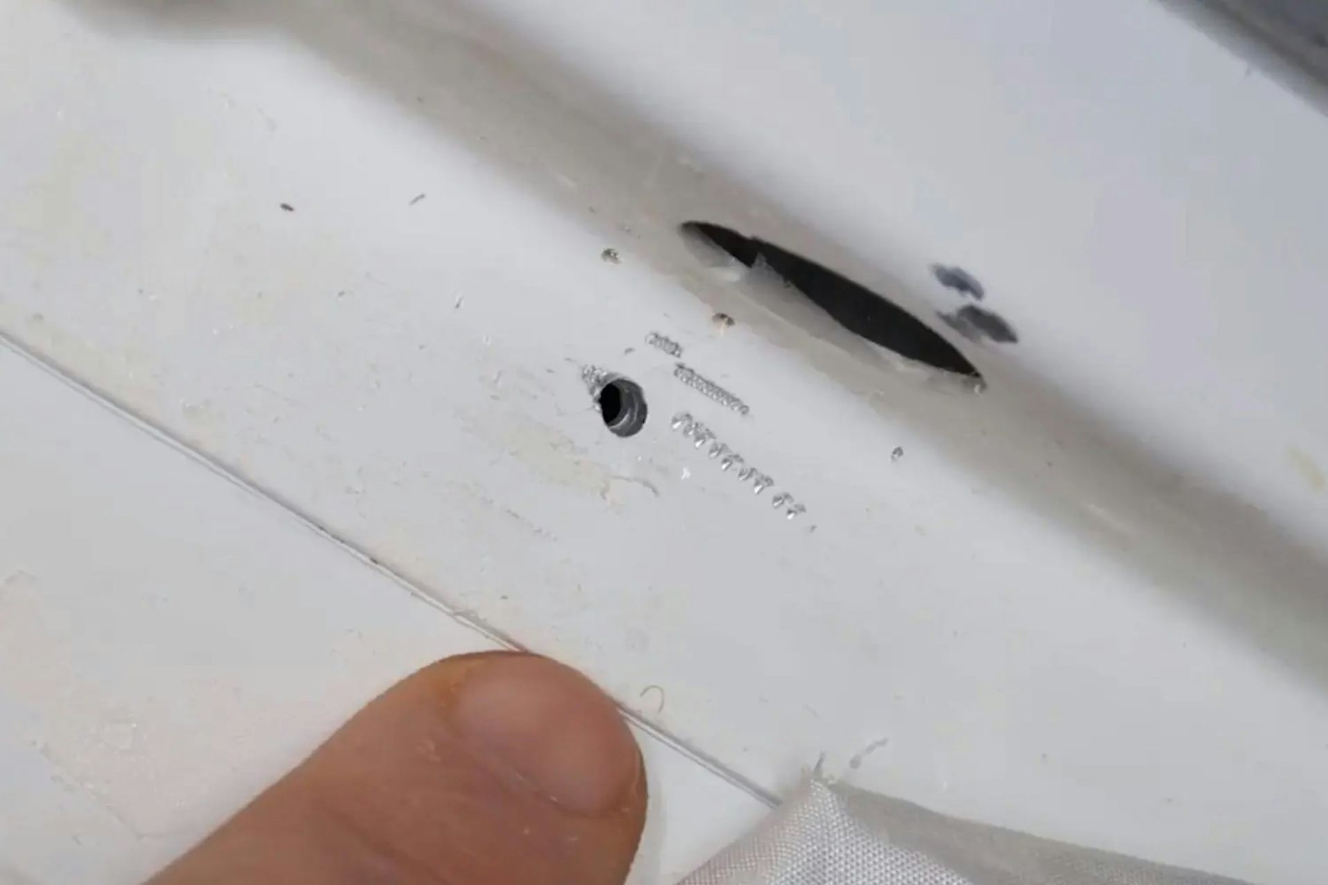 A small hole the size of a golf tee head in white material.