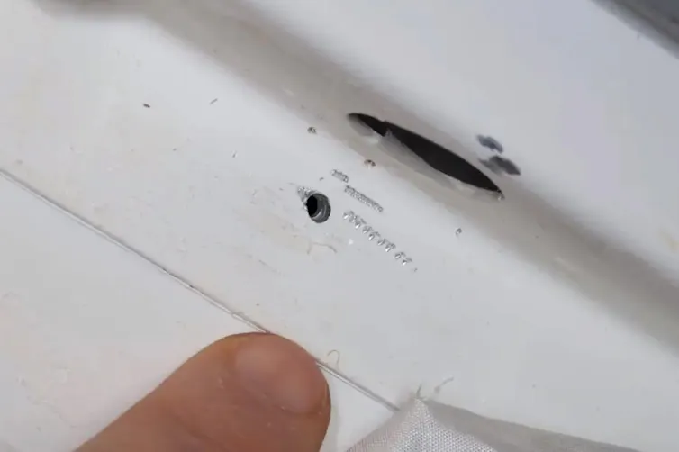 A small hole the size of a golf tee head in white material.