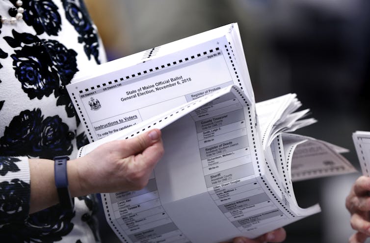 A person flips through tabulated ballots.