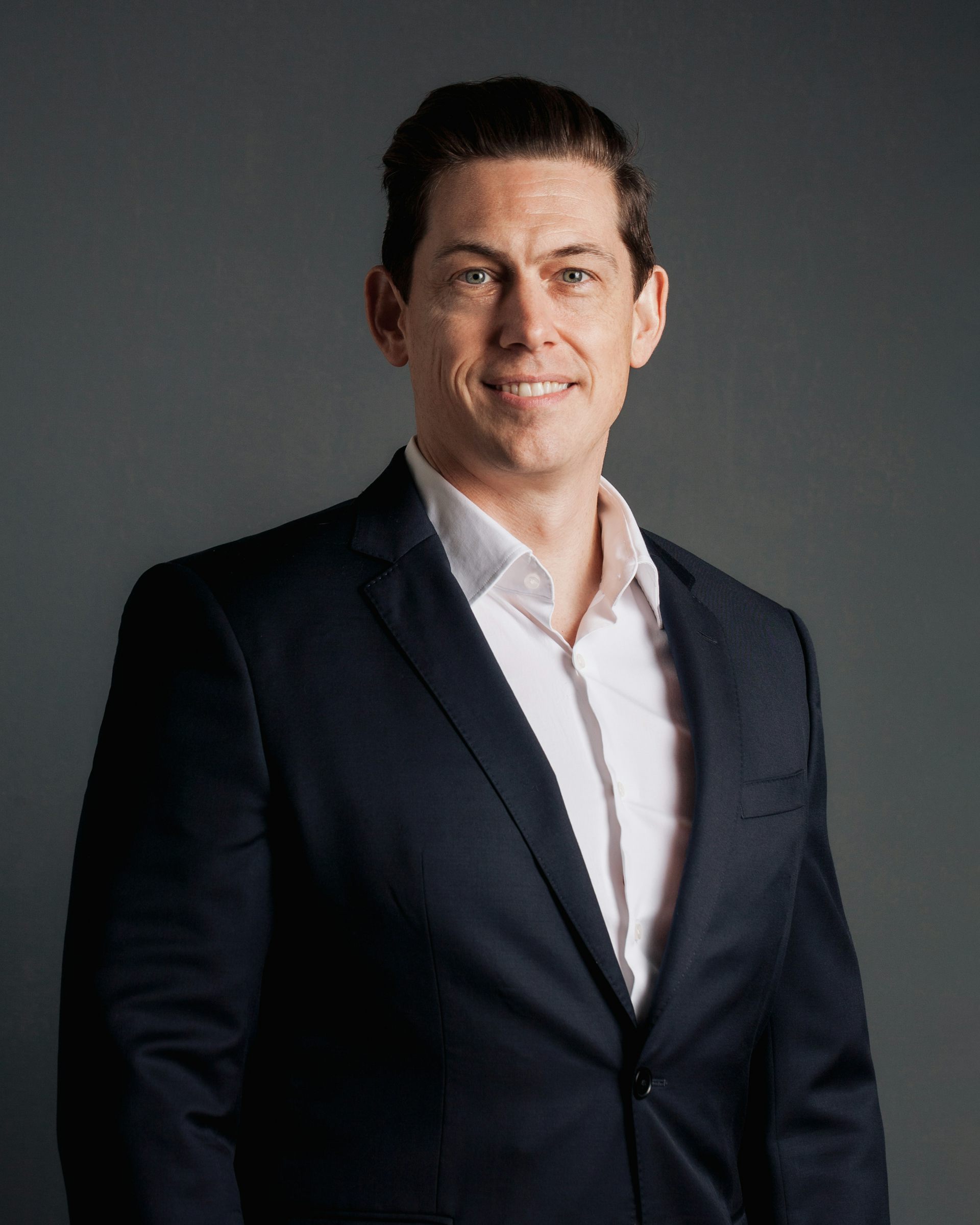 Portrait of man wearing suit jacket smiling.