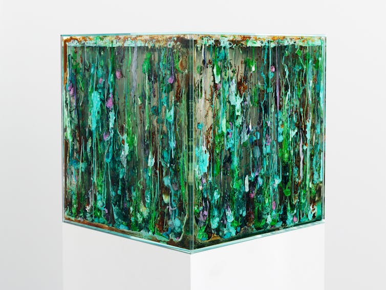 A sculpture of a cube in many shades of green.