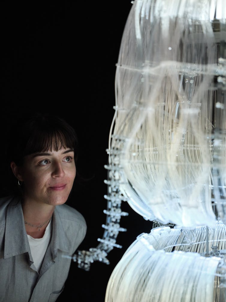 A woman leans in close to a jellyfish sculpture.