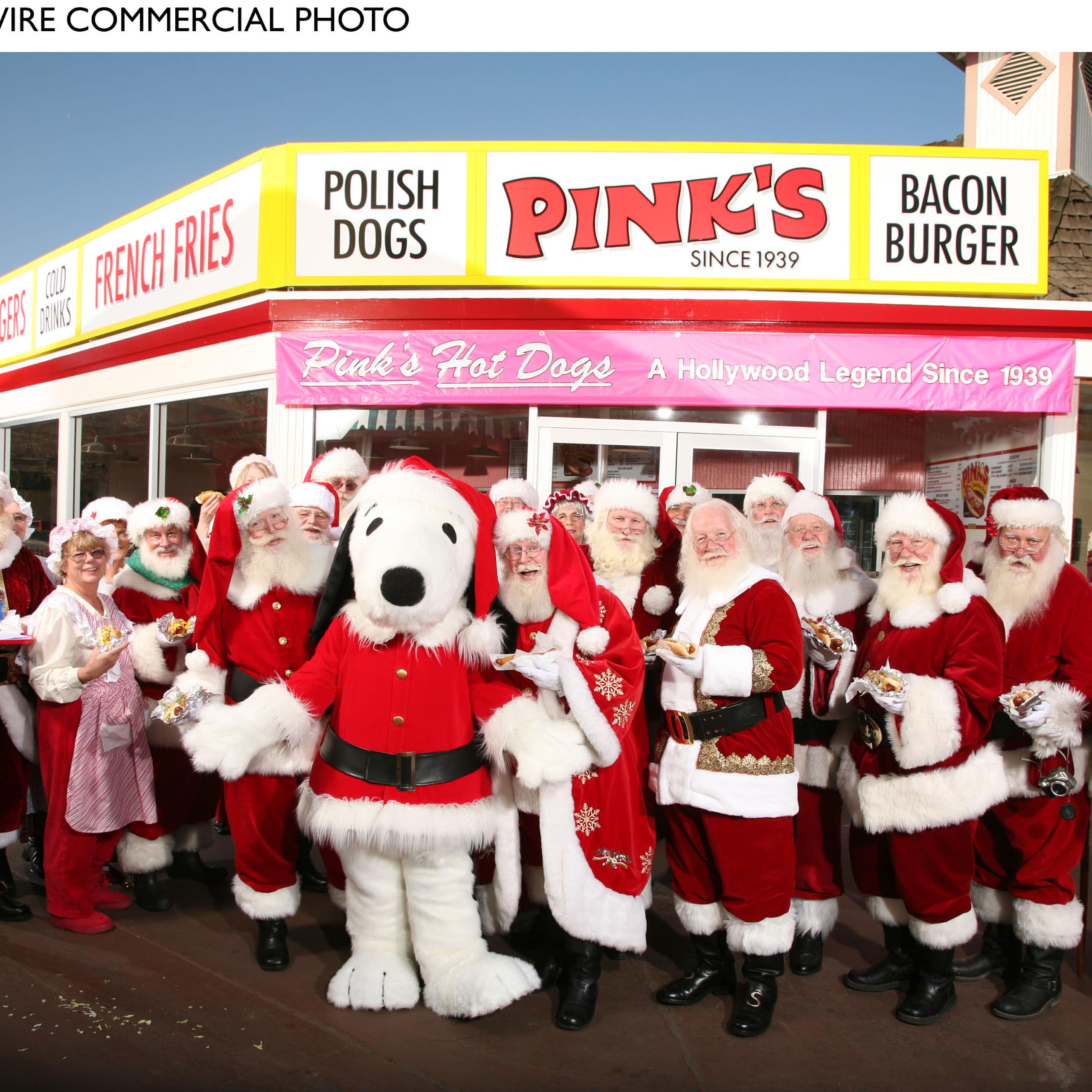 A group of Santas, including a Snoopy Santa, pose for a photo in front of a rural restaurant.
