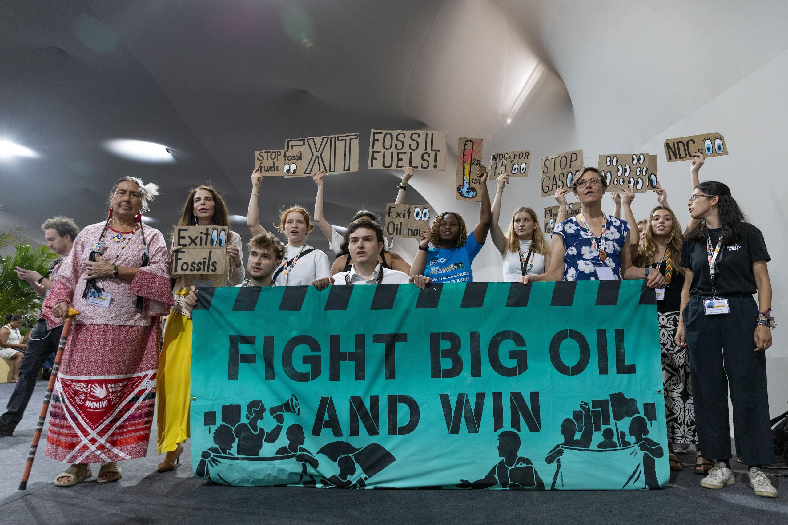Grupo de personas con carteles y una gran pancarta que dice 'fight big oil and win