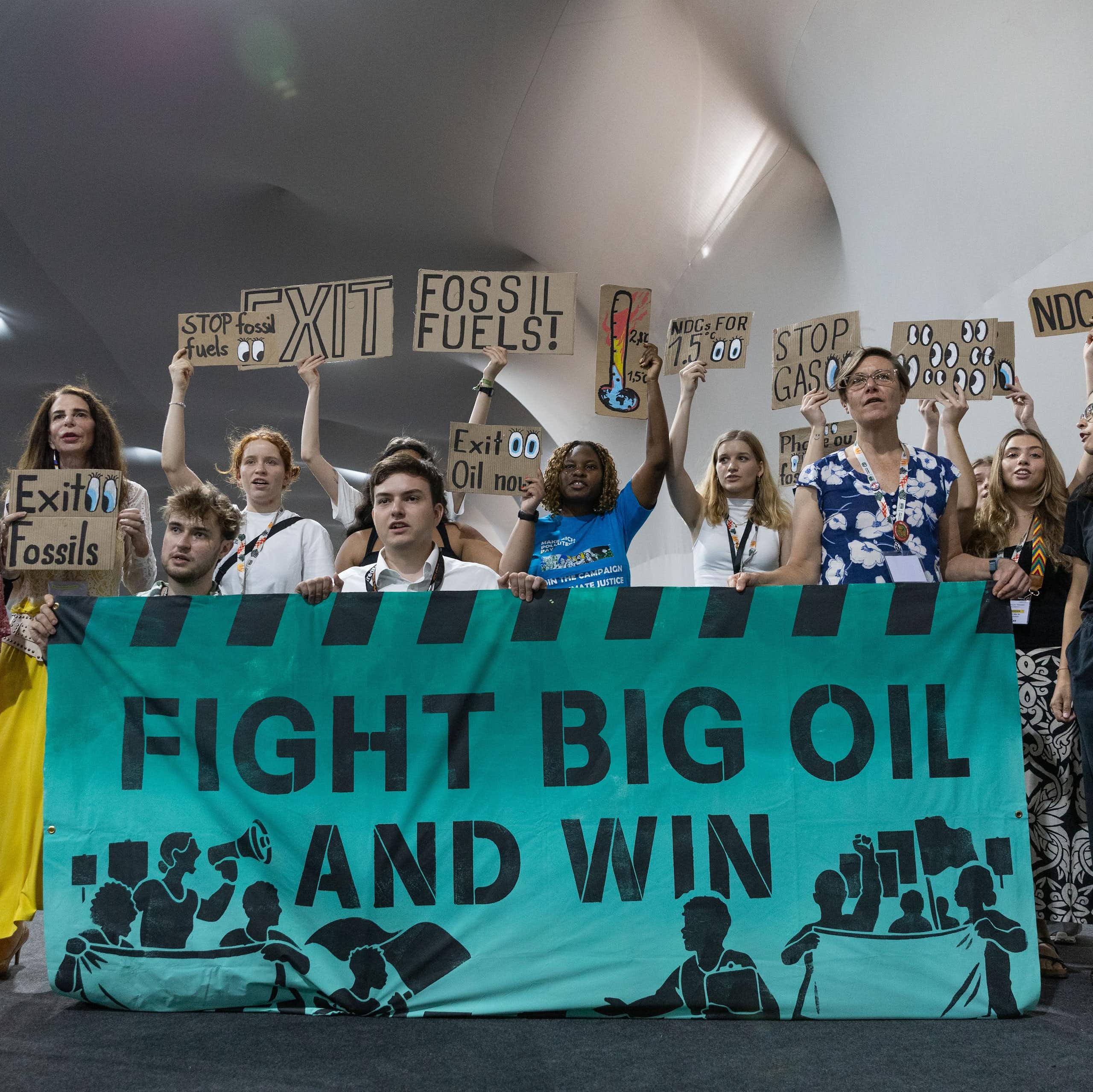 Grupo de personas con carteles y una gran pancarta que dice 'fight big oil and win