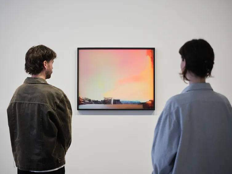 Two men look at an orange picture.