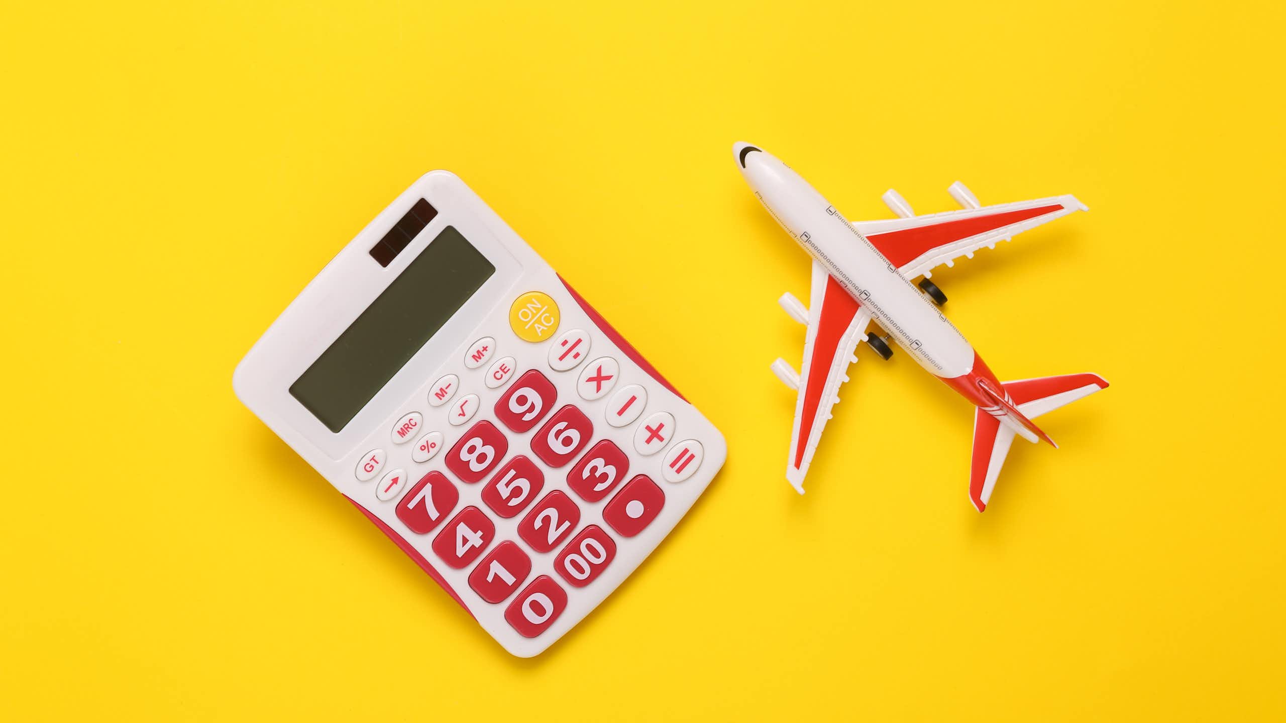 toy white and pink calculator and toy plane on bright yellow background