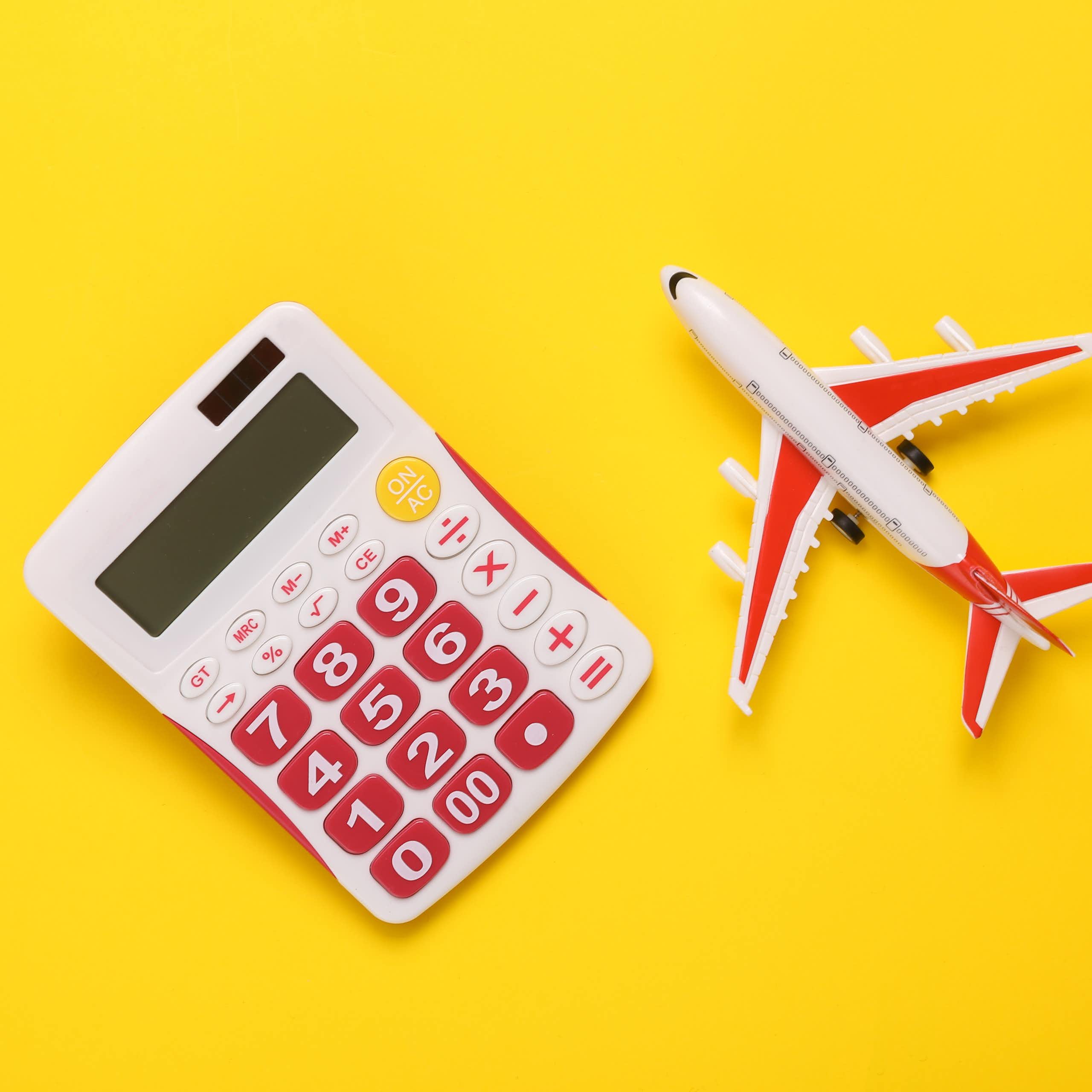 toy white and pink calculator and toy plane on bright yellow background