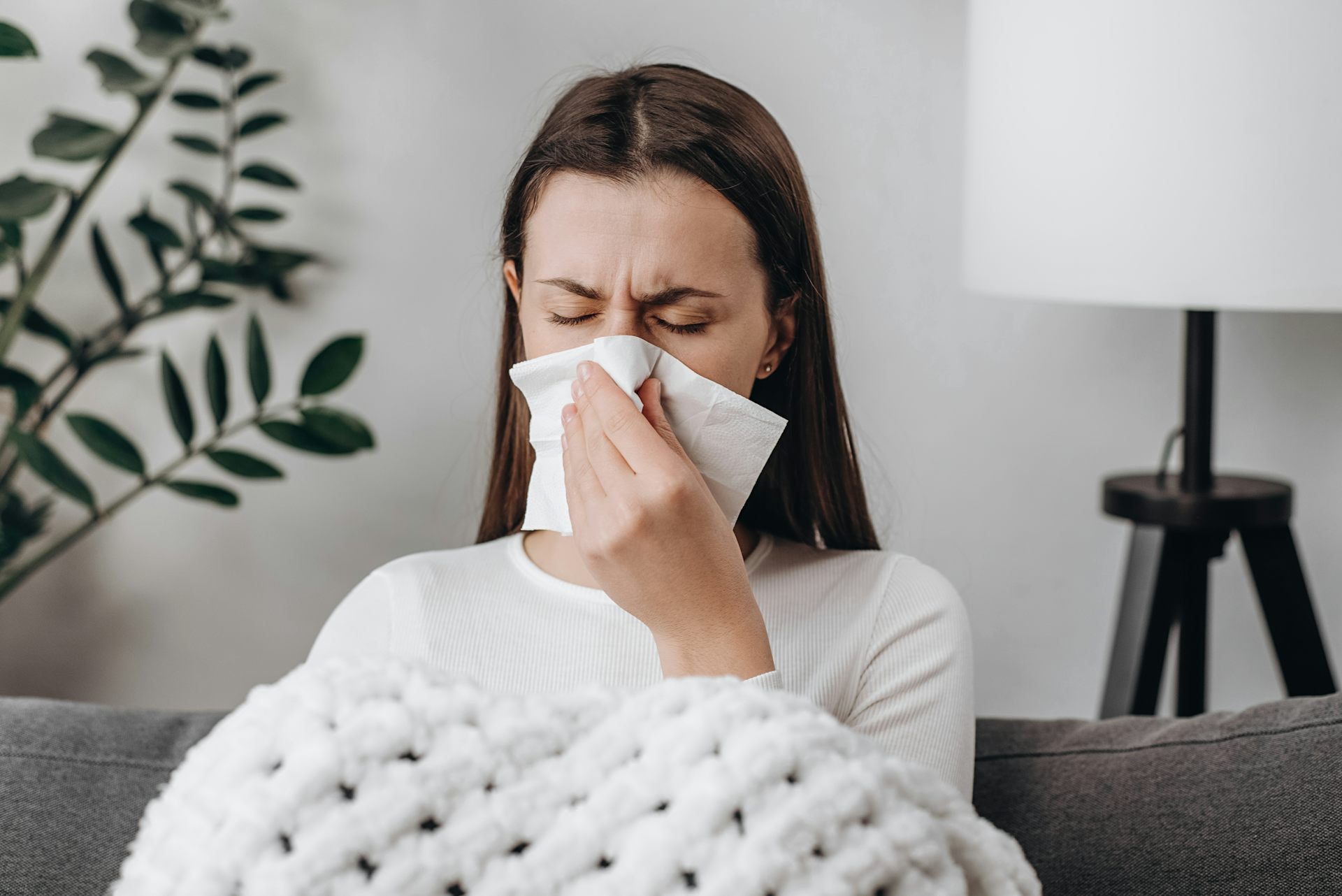 Una mujer enferma se suena la nariz.