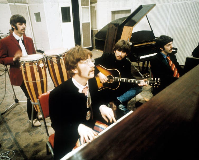 Starr plays drums, Lennon plays piano, Harrison plays guitar and Paul sits to the side.