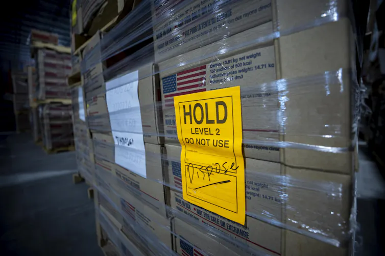 Stacks of boxes sit with a bright yellow label saying 'Hold, do not use, dispose.'