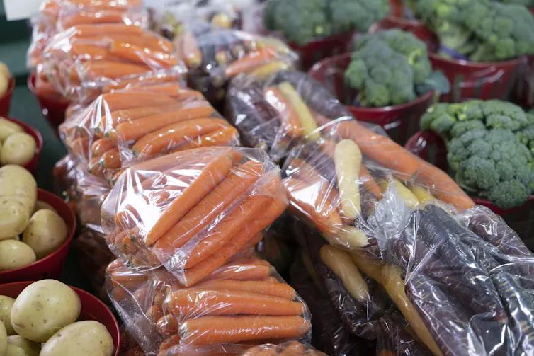 Vegetables wrapped in plastic bags in a grocery store.