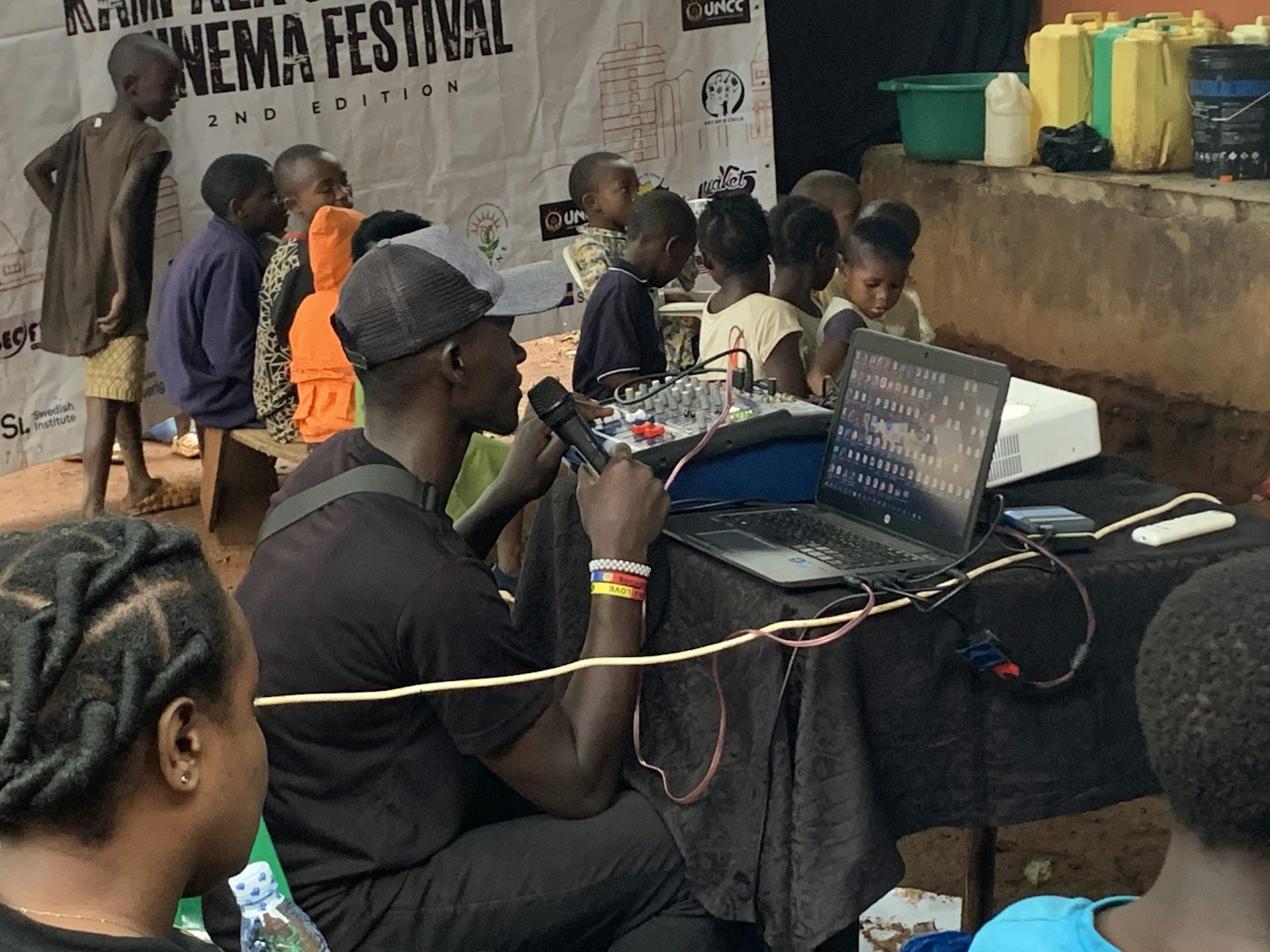 A man sits at a laptop with a microphone