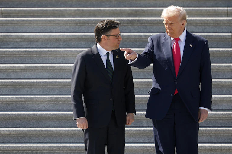 Two men in dark suits outside on stone stairs.