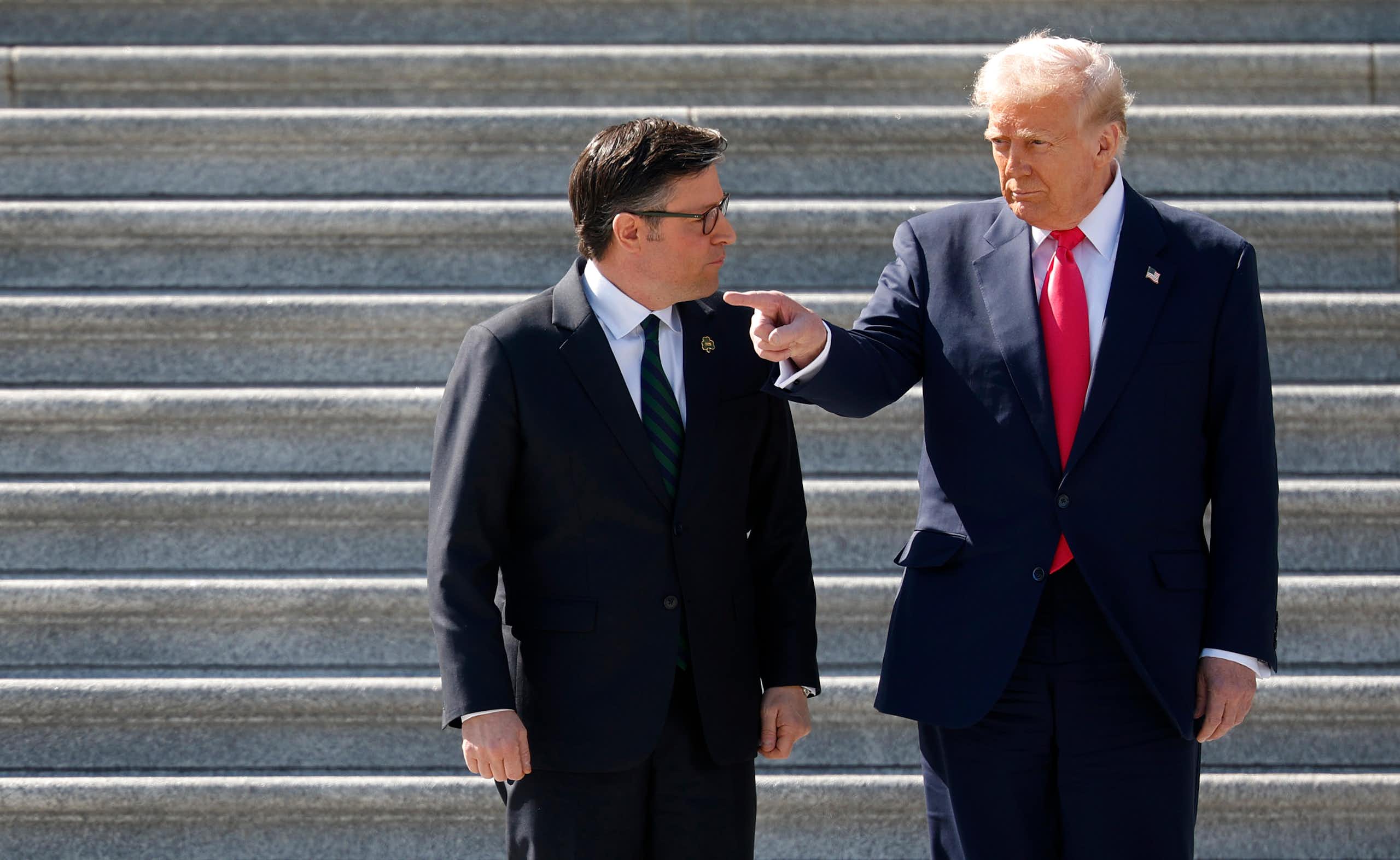 Two men in dark suits outside on stone stairs.