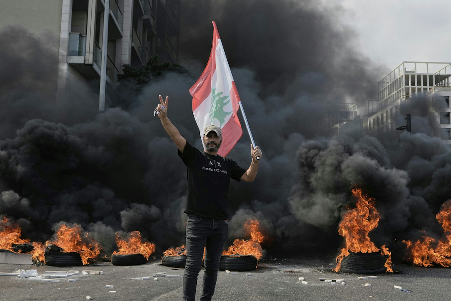A protester holds a flag in front of burning tires.
