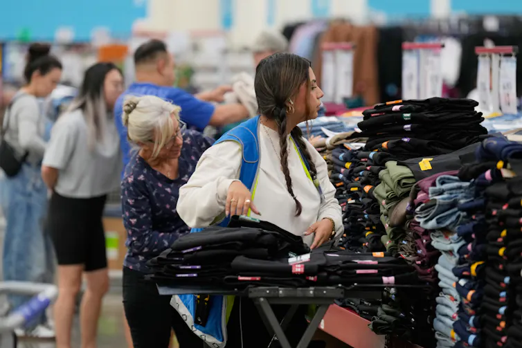 Un employé rangeant des piles de jeans dans un magasin de vêtements