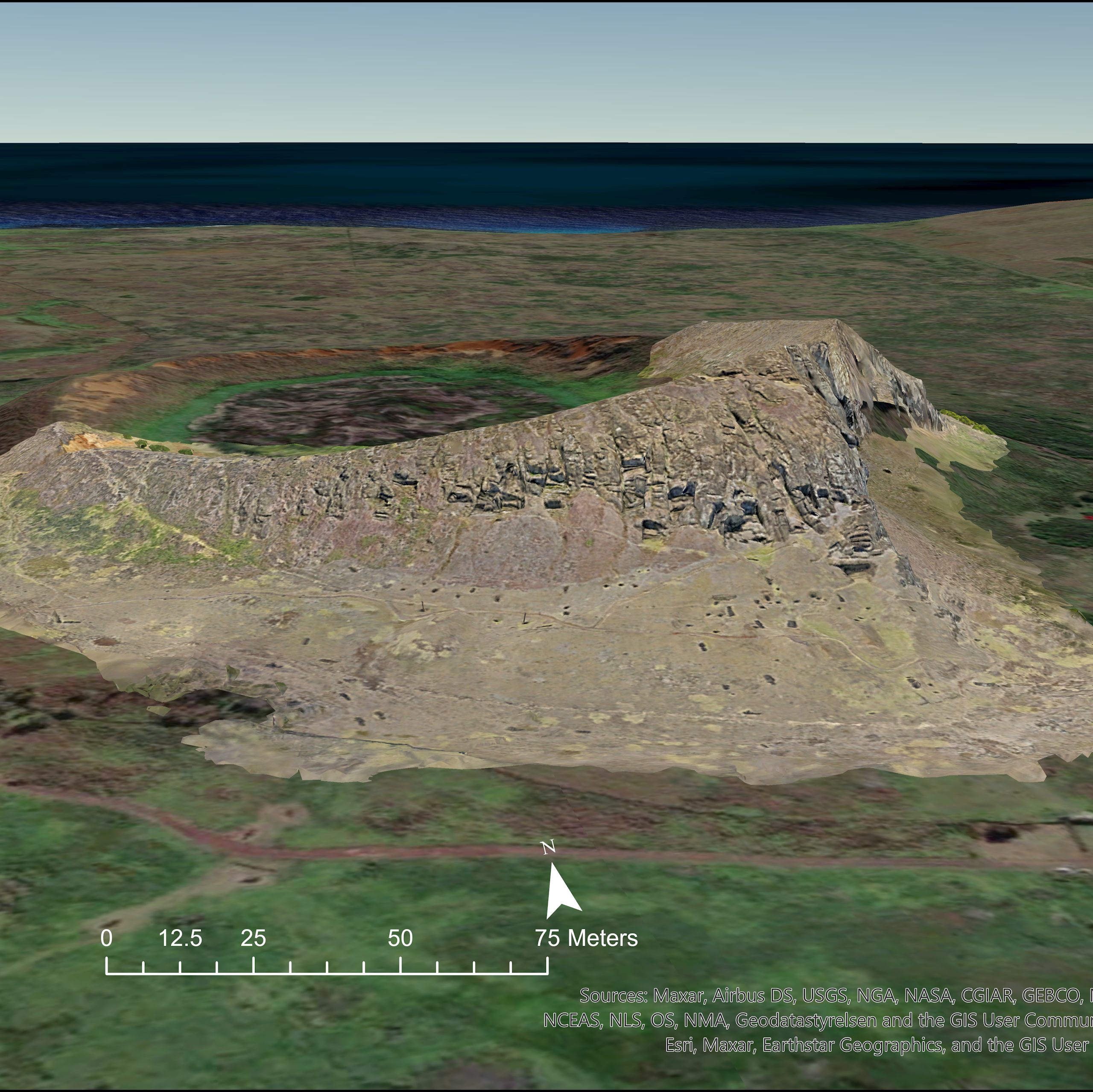 aerial view of a rocky hillside in a treeless landscape with the ocean in the background