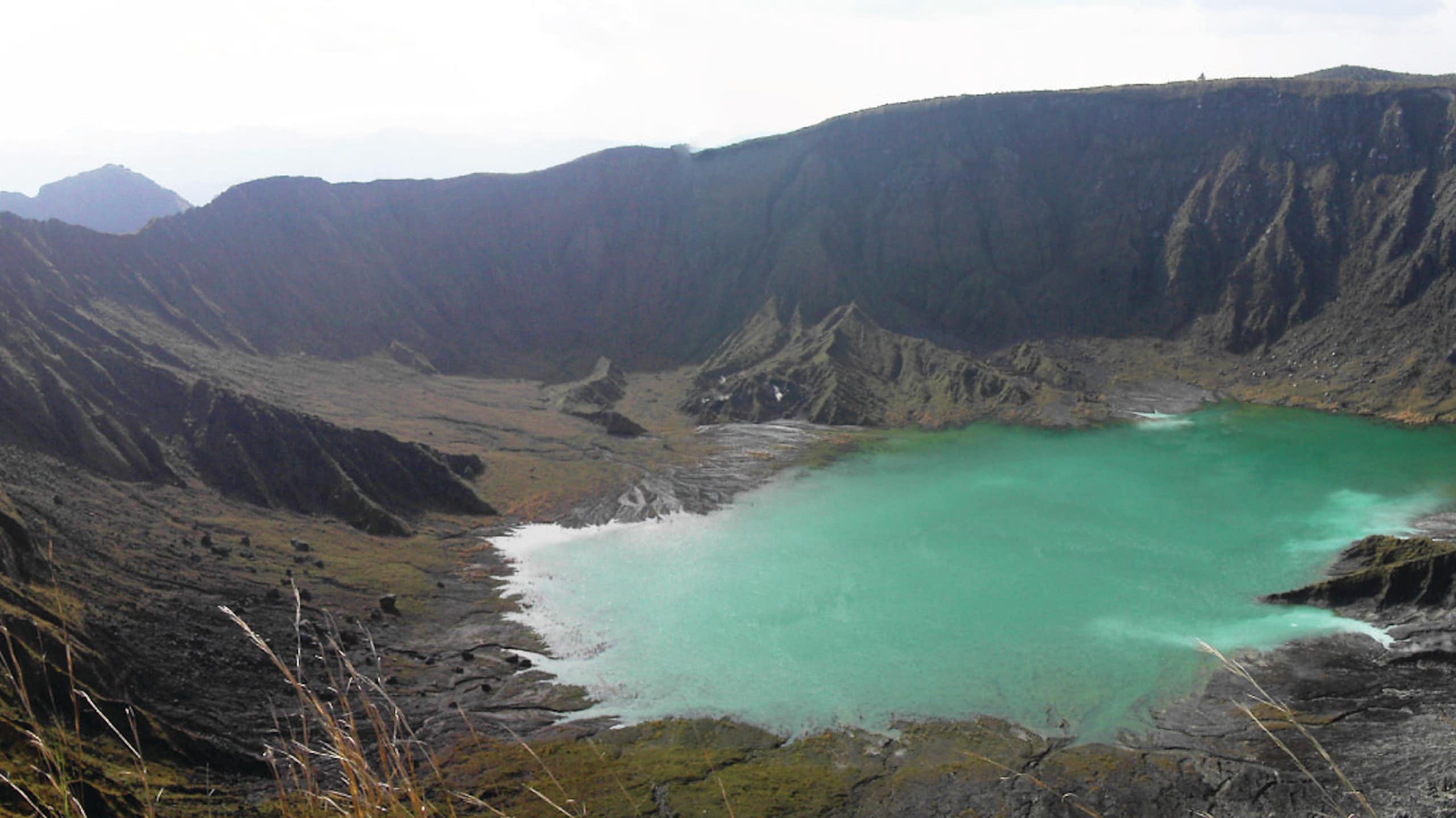 vulcão, lago azul no topo da montanha, céu cinzento
